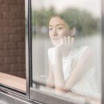 窓辺でひとり静かに考えごとをする女性