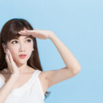 紫外線を避けるように手で日差しを遮る女性